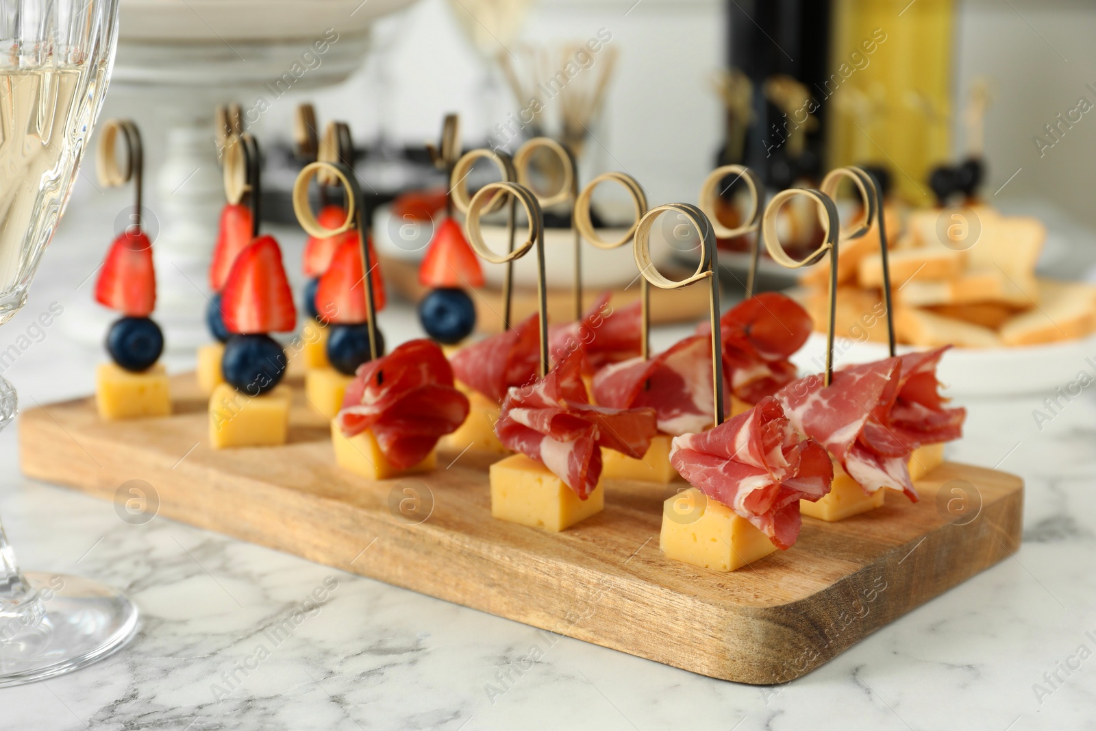 Photo of Different tasty canapes on white marble table, closeup