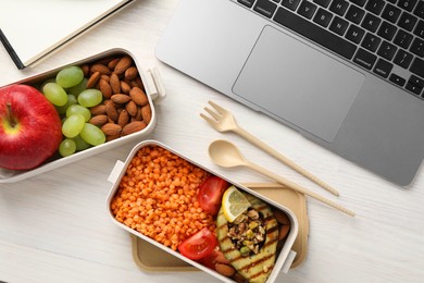 Photo of Healthy products high in vegetable fats near laptop on light wooden table, flat lay