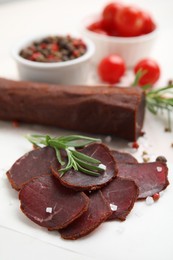 Photo of Delicious dry-cured beef basturma with rosemary and spices on table, closeup