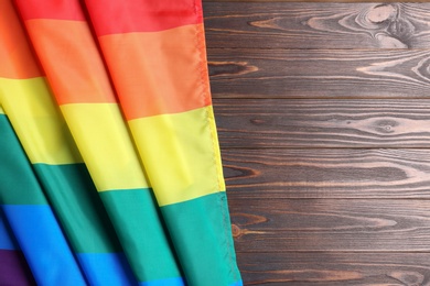 Bright rainbow gay flag on wooden background, top view with space for text. LGBT community