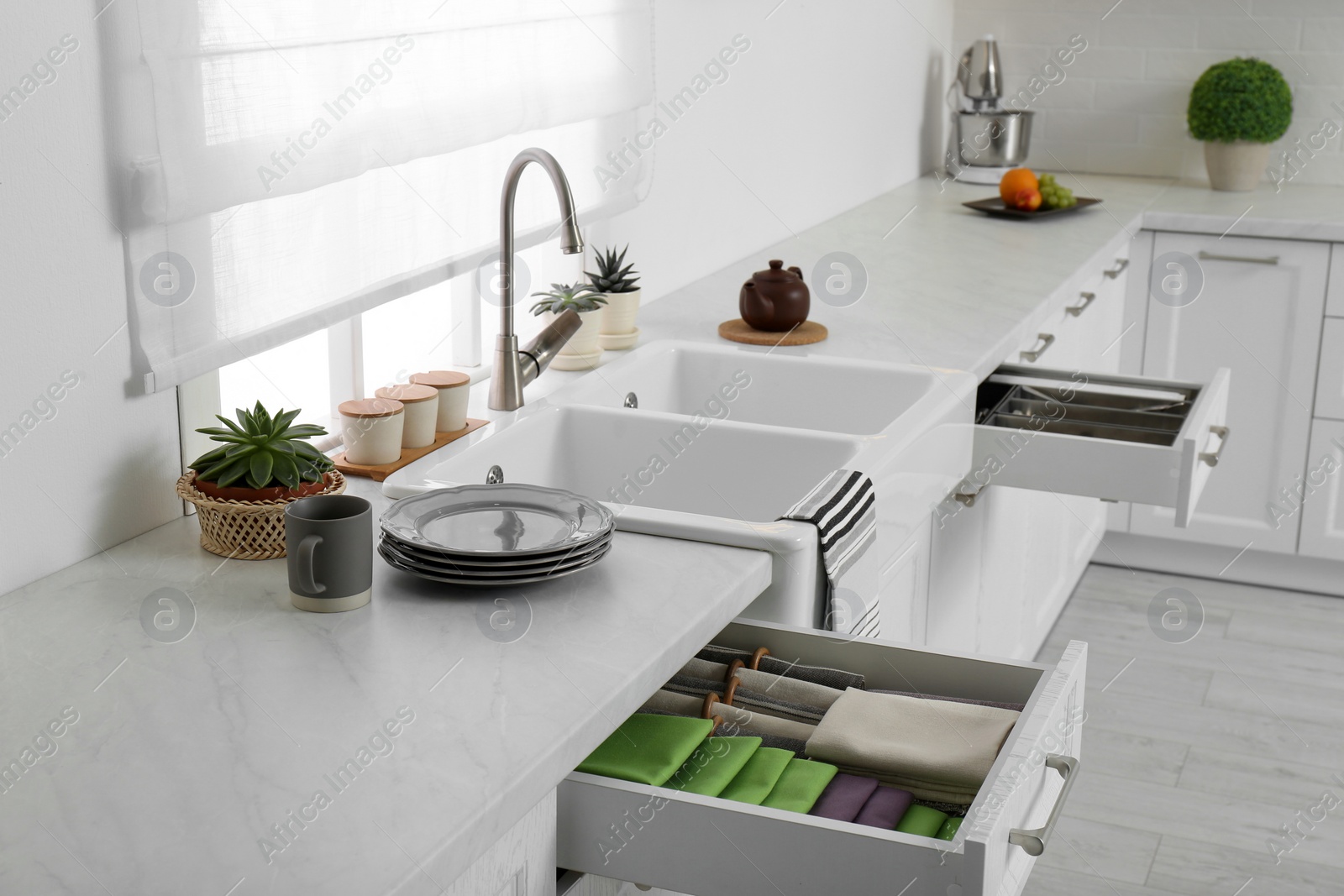 Photo of Open drawers with different utensils, towels and napkins in kitchen