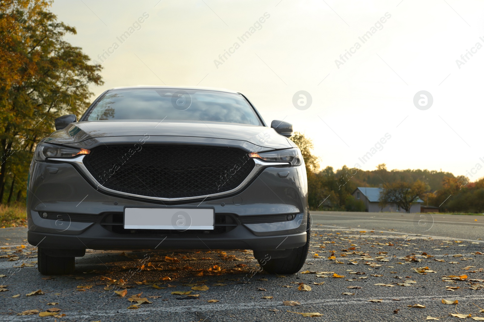 Photo of Black modern car parked on road at sunset