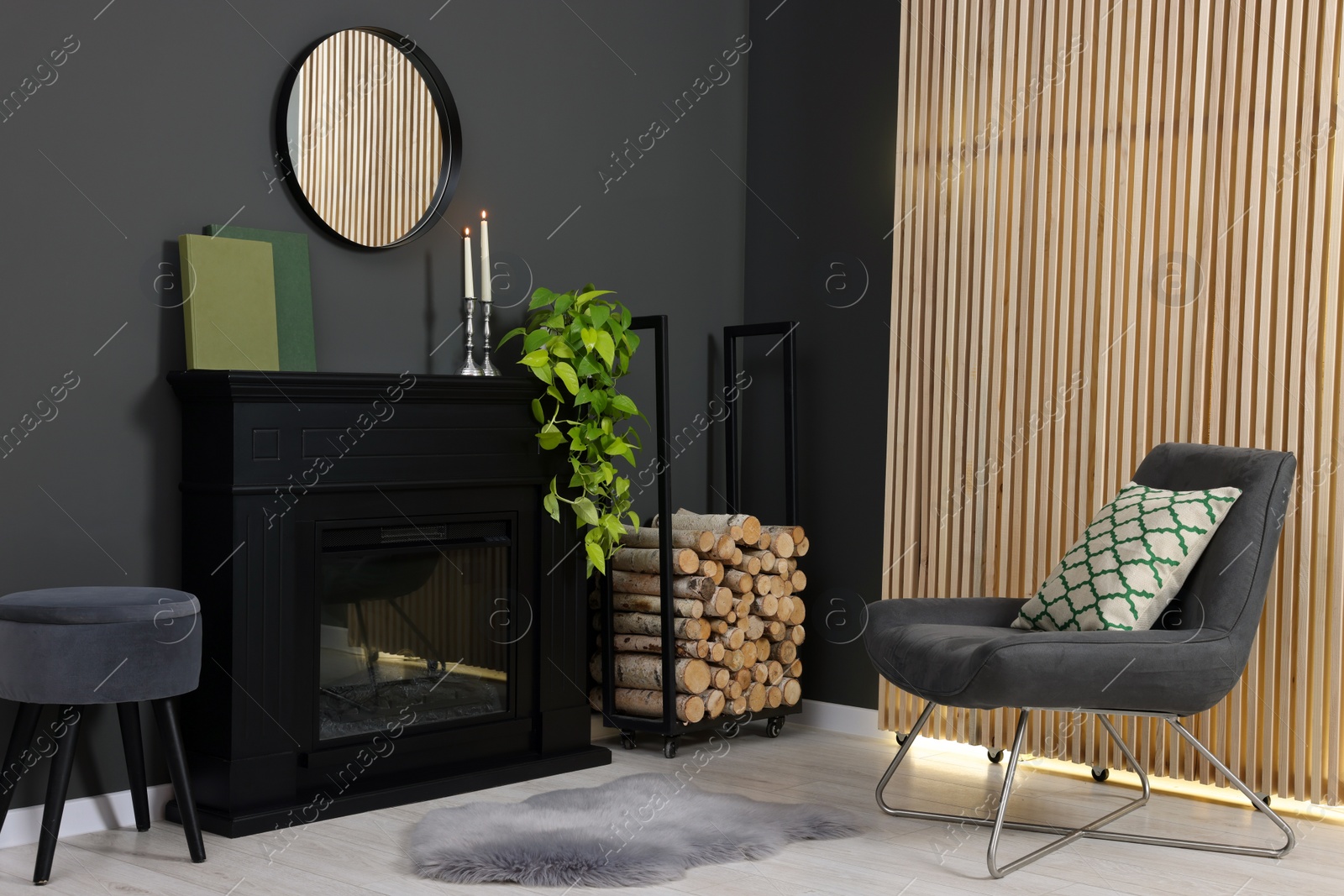 Photo of Stylish room with beautiful fireplace, houseplant and comfortable chair. Interior design