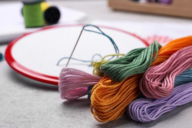 Photo of Different threads and embroidery hoop on light grey table
