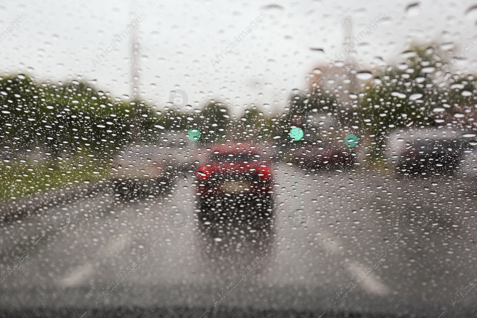 Photo of Blurred view of road through wet car window. Rainy weather