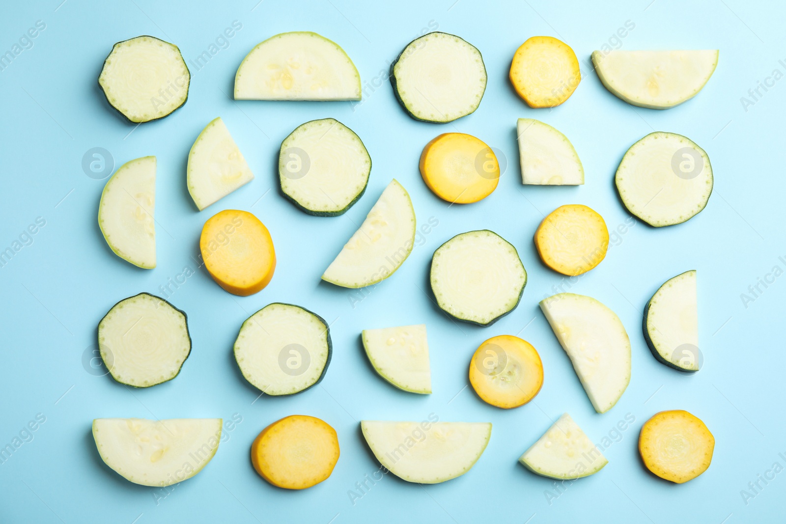 Photo of Fresh ripe cut zucchinis on light blue background, flat lay