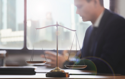 Image of Scales of justice and blurred lawyer working on background