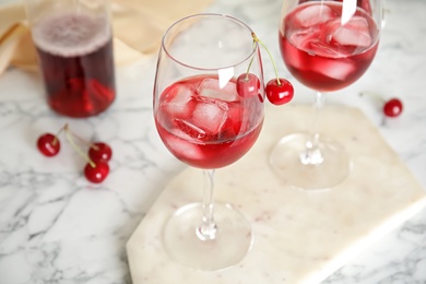 Delicious cherry wine with ripe juicy berries on white marble table