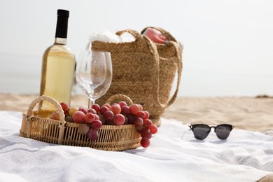 Photo of Bag, blanket, wine and other stuff for beach picnic on sandy seashore