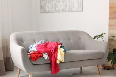 Photo of Pile of clothes on sofa in dressing room. Renew wardrobe