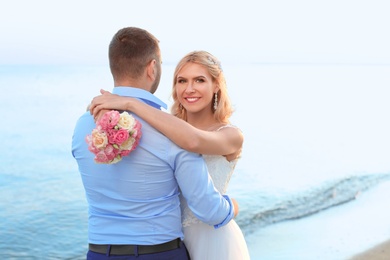 Wedding couple hugging on beach. Space for text