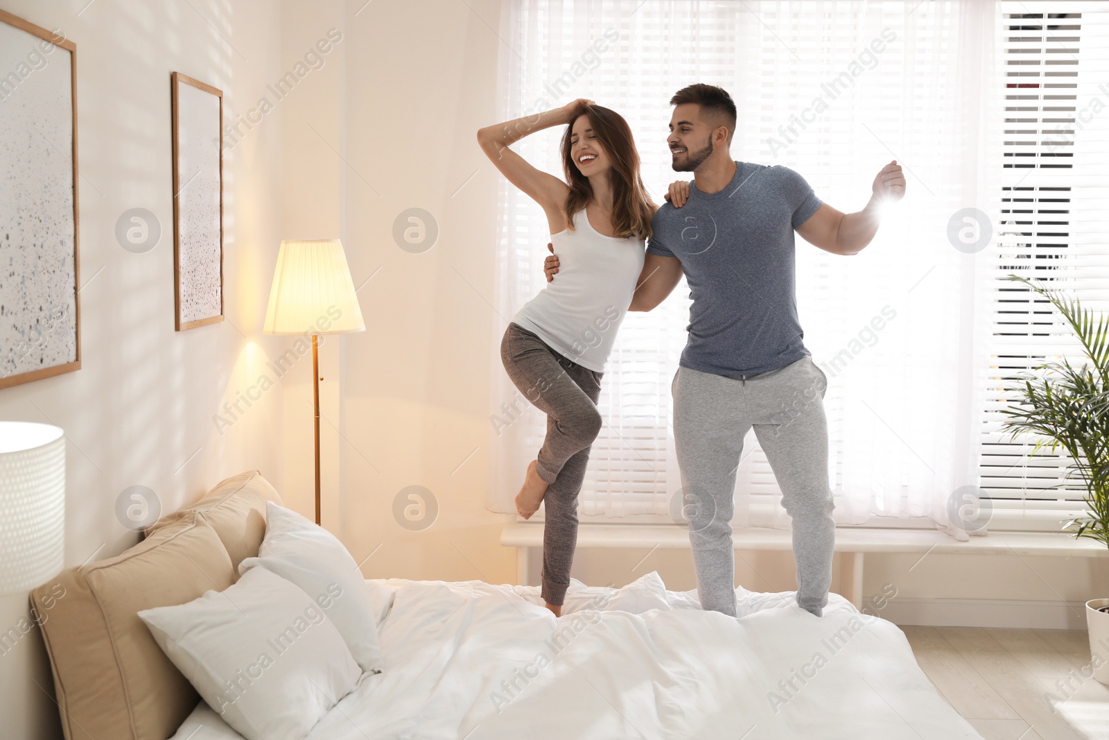 Photo of Lovely young couple dancing on bed at home