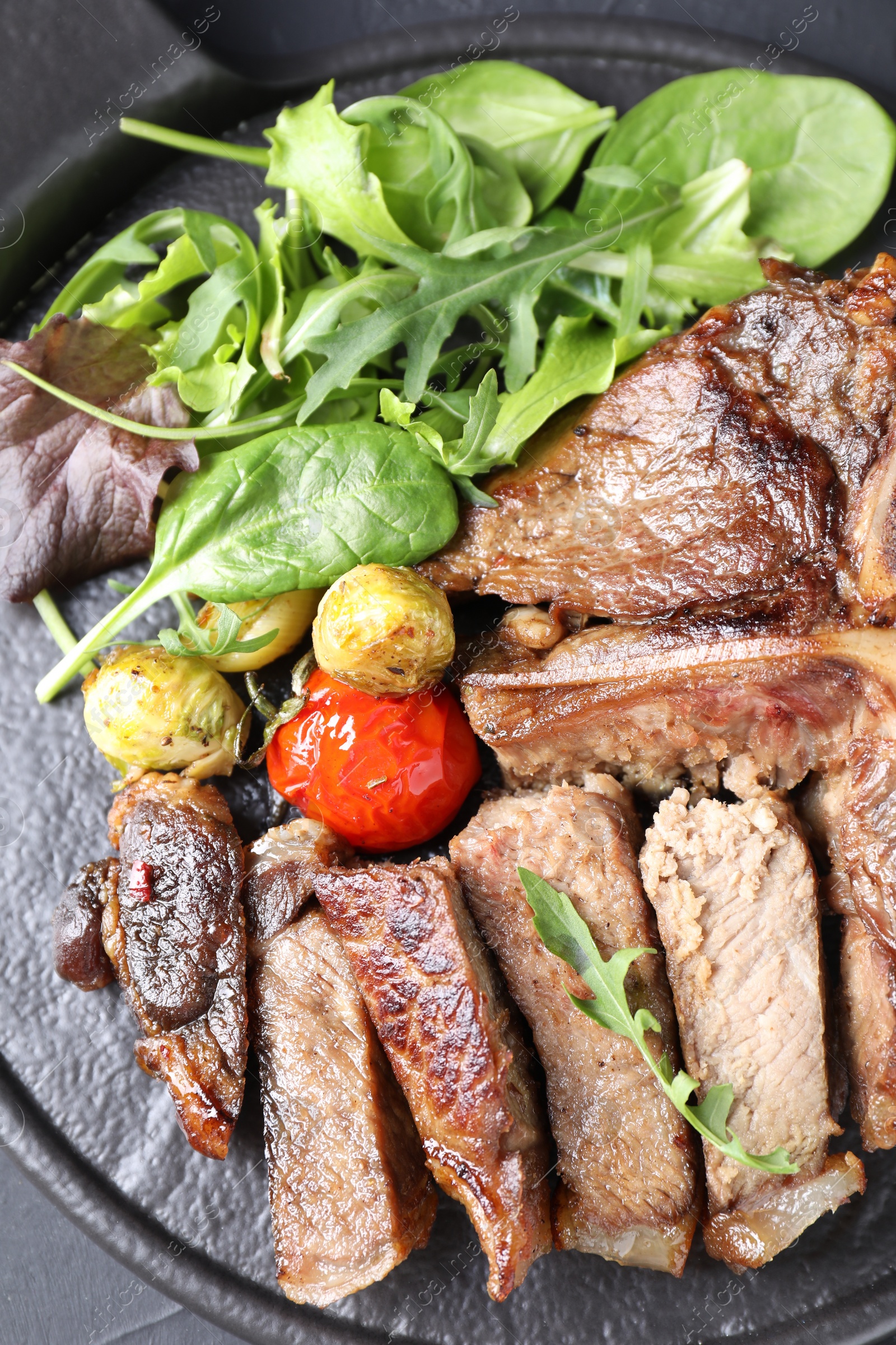 Photo of Delicious grilled beef meat, vegetables and greens on table, top view