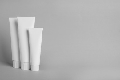 Photo of Blank tubes of toothpaste on light grey background. Space for text