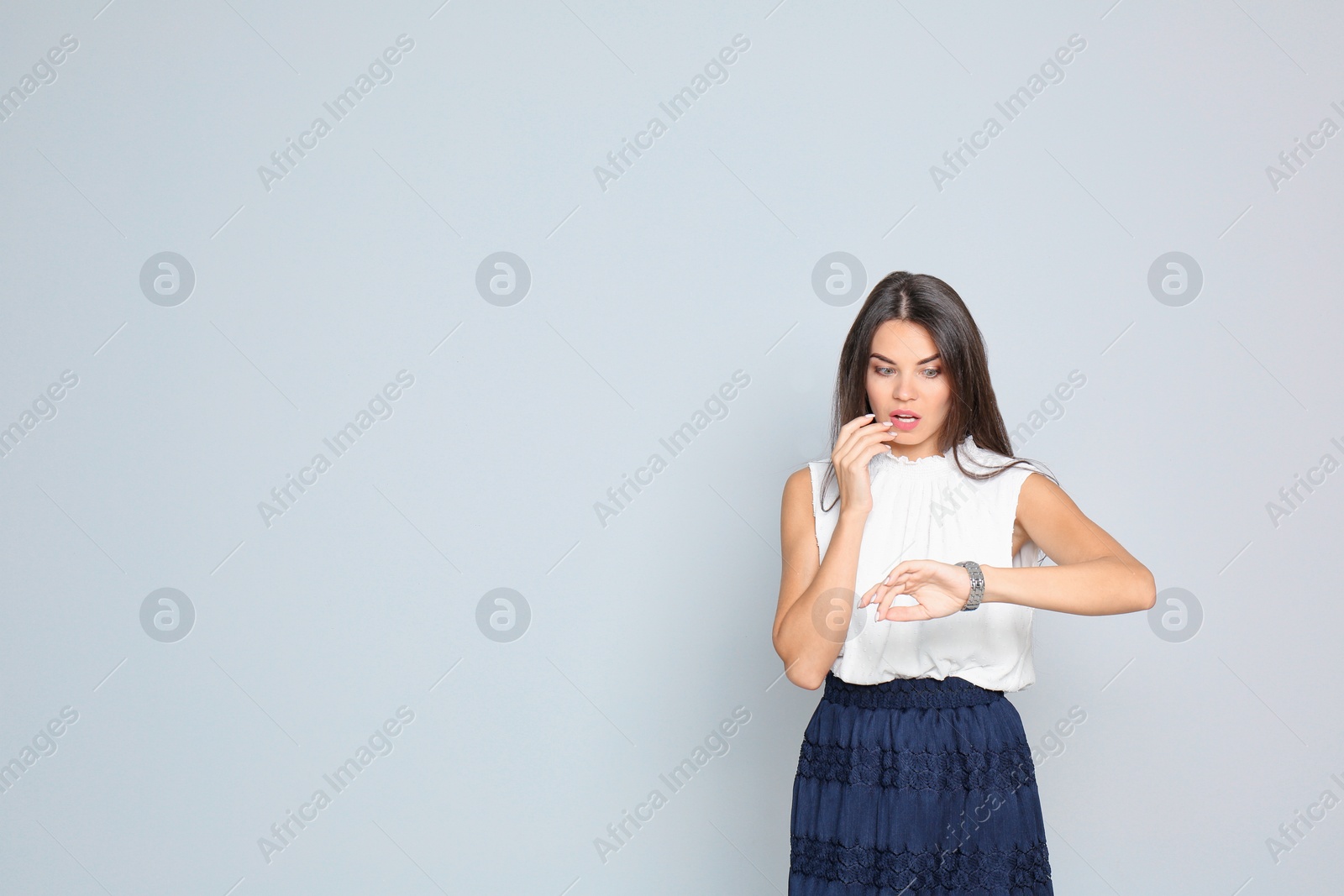 Photo of Beautiful woman with watch wearing office clothes against gray background. Space for text