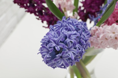 Photo of Beautiful hyacinths in glass vase on blurred background, space for text. Spring flowers