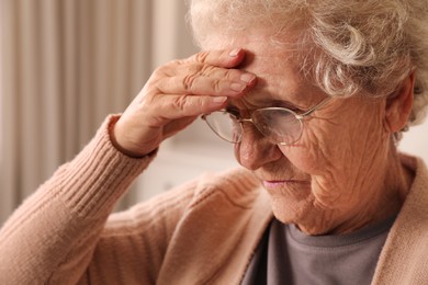 Photo of Senior woman with headache at home, closeup. Symptom of age-related memory impairment