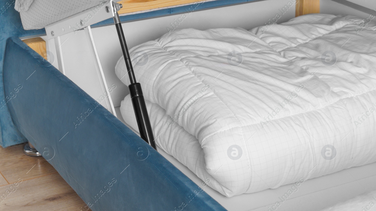 Photo of Storage drawer under bed with white blanket indoors, closeup