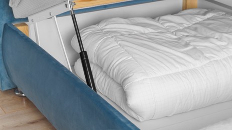Photo of Storage drawer under bed with white blanket indoors, closeup