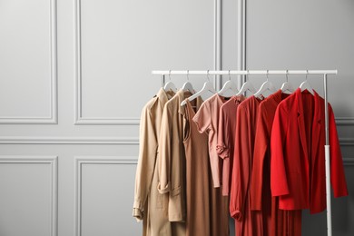 Photo of Rack with different stylish women`s clothes near grey wall, space for text