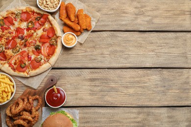 Photo of Pizza, onion rings and other fast food on wooden table, flat lay with space for text
