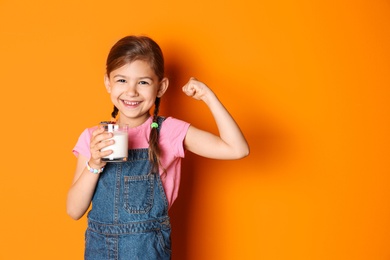 Cute little girl with glass of milk on color background