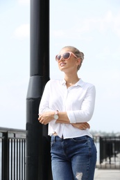 Beautiful young woman with sunglasses standing at pier. Joy in moment
