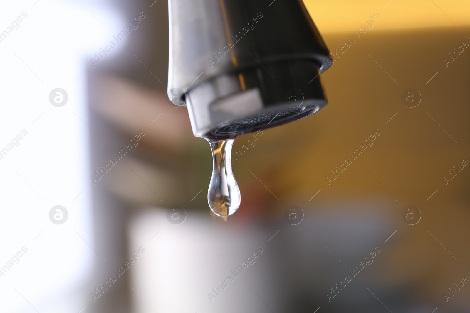 Photo of Water drop falling down from tap on blurred background, closeup