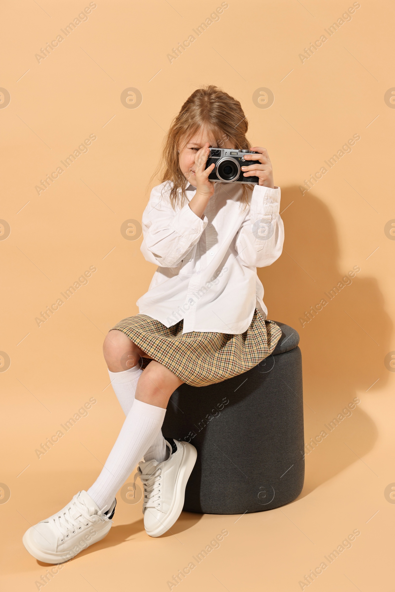 Photo of Fashion concept. Stylish girl with camera on pale orange background