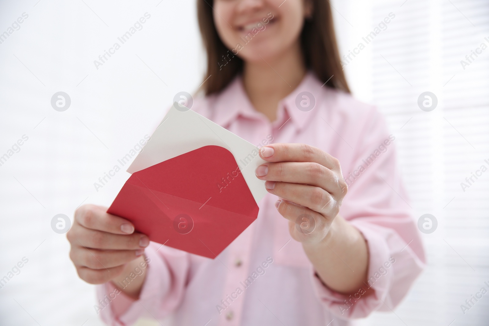 Photo of Woman holding envelope with blank greeting card at home, closeup