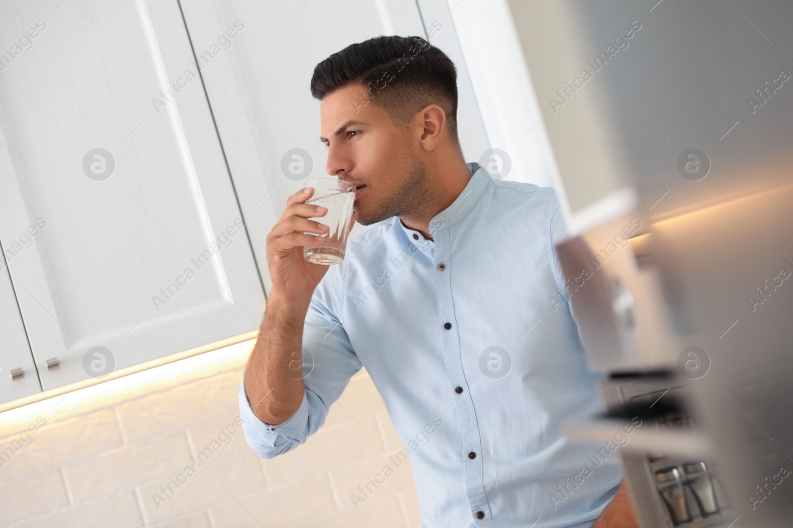 Photo of Man drinking pure water from glass in kitchen