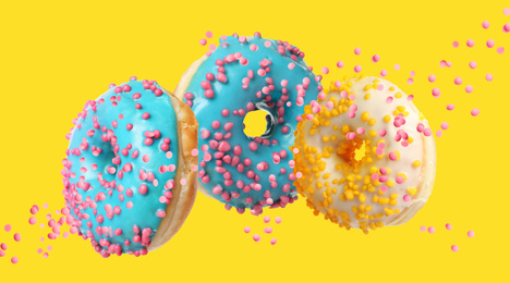 Image of Set of falling delicious donuts on yellow background