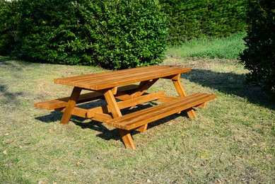 Photo of Empty wooden picnic table with benches in park on sunny day