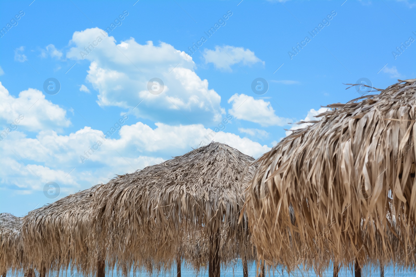 Photo of Beautiful straw beach umbrellas against blue sky
