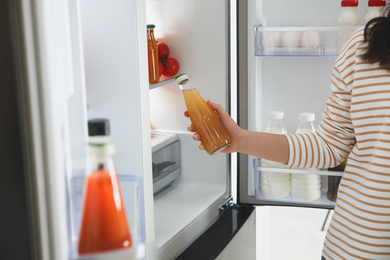 Photo of Young woman taking juice out of refrigerator, closeup