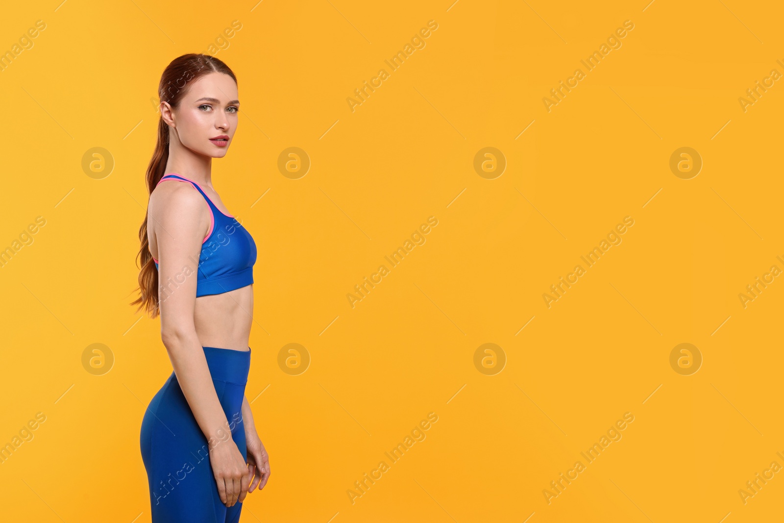 Photo of Young woman wearing sportswear on yellow background, space for text