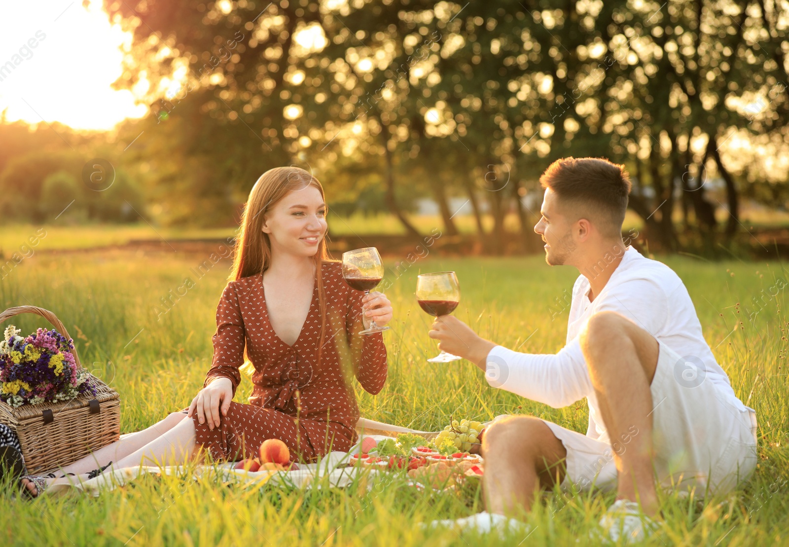 Photo of Young man and his girlfriend having picnic in green park