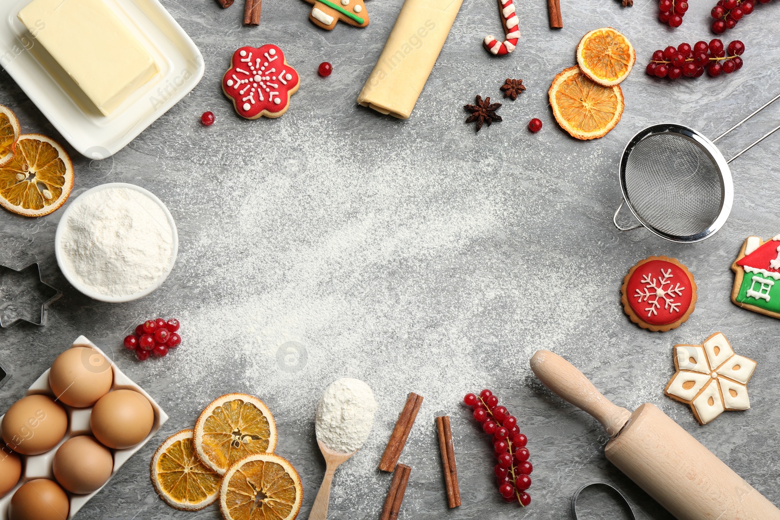 Photo of Frame of Christmas cookies and flour on grey table, flat lay. Space for text