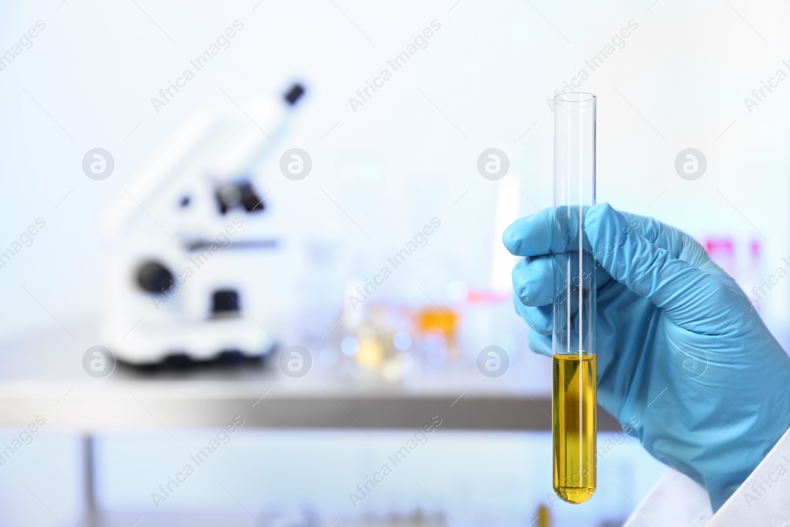 Photo of Laboratory assistant holding urine sample in test tube indoors, closeup with space for text. Medical analysis