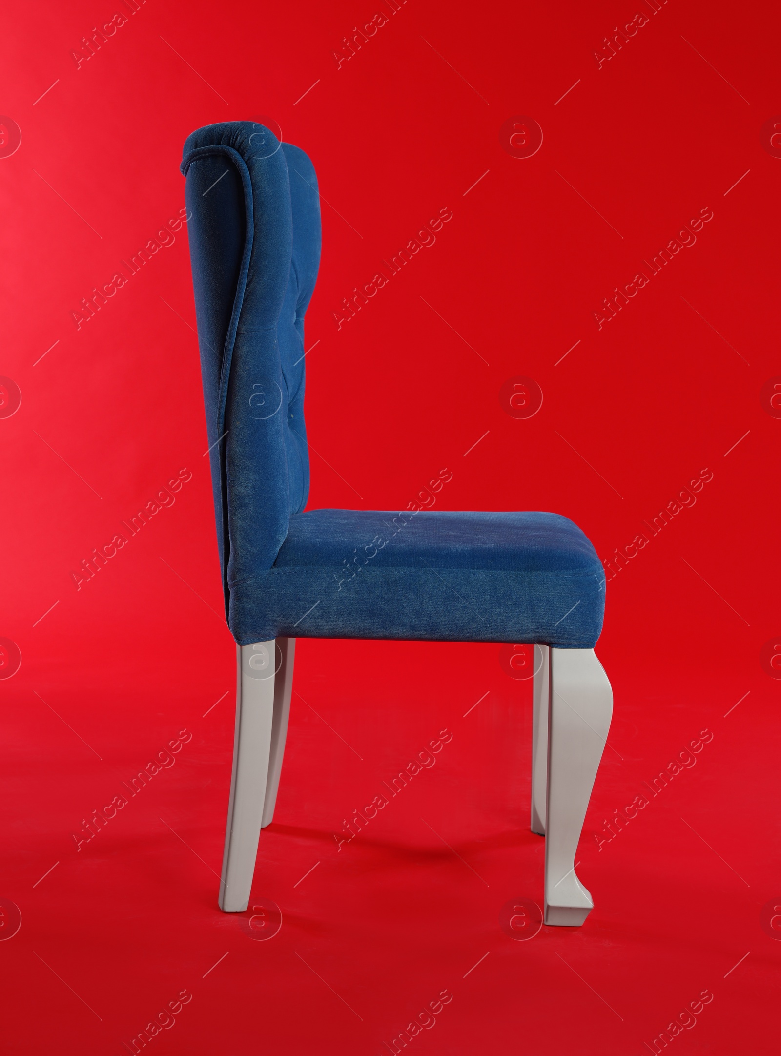 Photo of Stylish blue chair on red background. Element of interior design