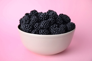 Photo of Fresh ripe blackberries in bowl on pink background