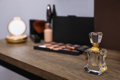 Bottle of perfume and cosmetics on wooden table. Space for text