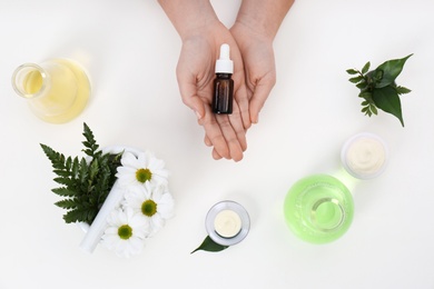 Photo of Female dermatologist with bottle of skin care product and ingredients on white background, top view