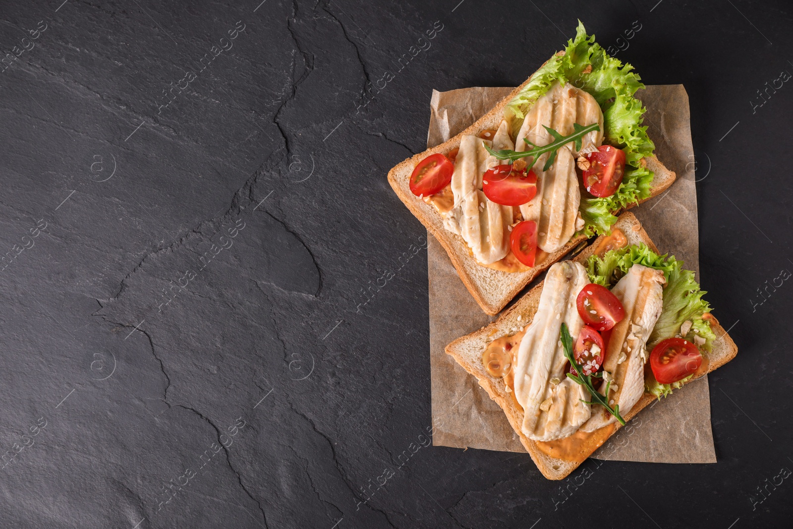 Photo of Delicious sandwiches on black table, top view. Space for text