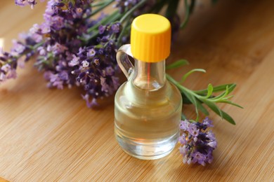Photo of Bottle of natural essential oil and lavender flowers on wooden table, closeup