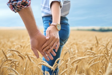 Photo of Young couple holding hands in grain field, closeup