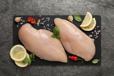 Photo of Raw chicken breasts and ingredients on grey table, top view