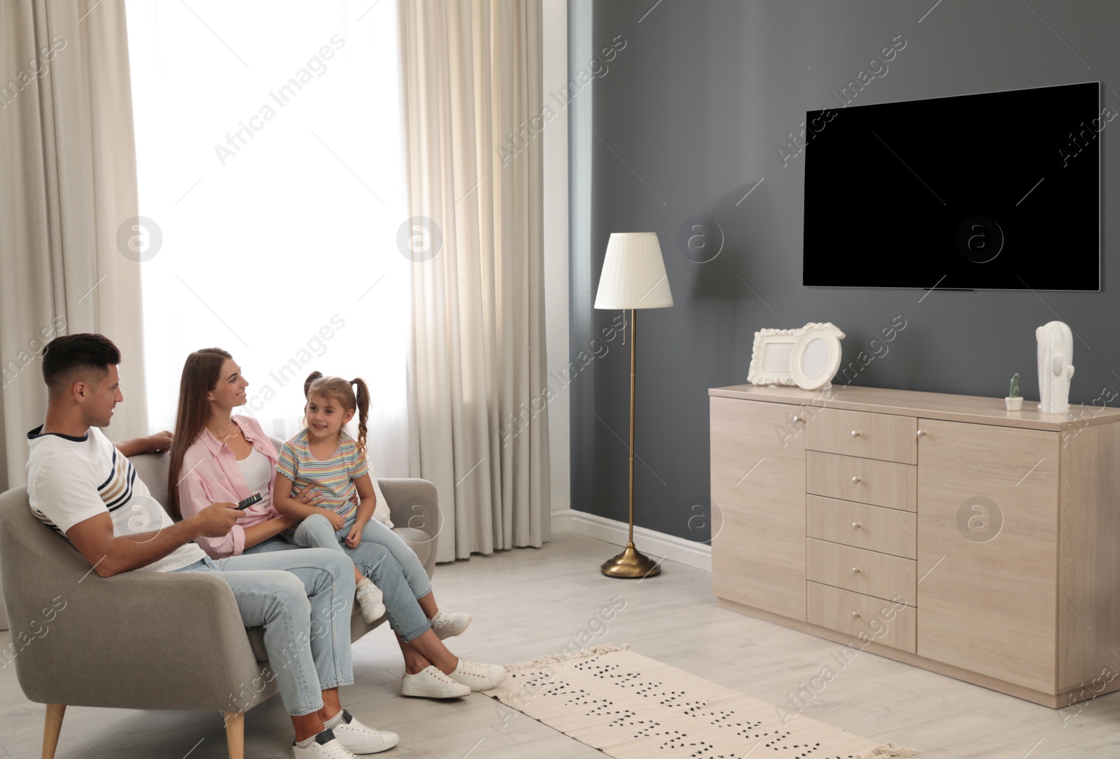 Photo of Happy family watching TV on sofa at home