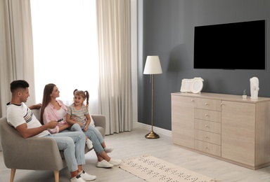 Photo of Happy family watching TV on sofa at home