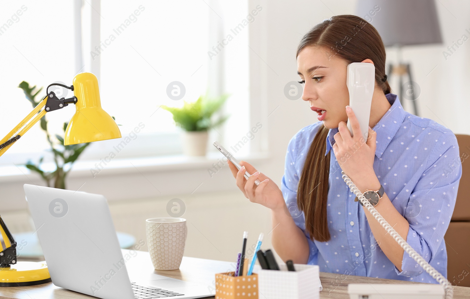 Photo of Young woman talking on phone at workplace